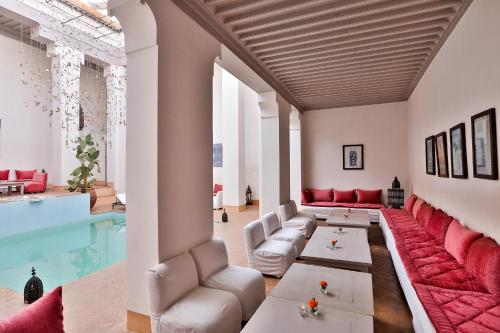 a living room with a pool and red furniture at Hotel & Spa Riad Al Jazira in Marrakech