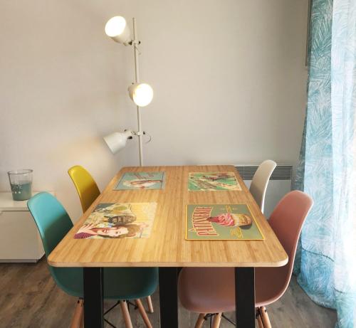 une table en bois entourée de chaises colorées. dans l'établissement Le Bellevue, à Cassis