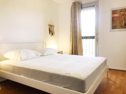 Una cama blanca en una habitación con ventana. en Le Bellevue, en Cassis