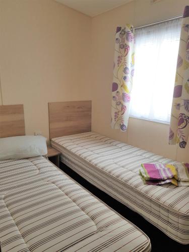 two beds sitting in a room with a window at 184 Unity Resort Brean in Brean