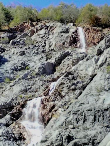 a waterfall on the side of a rocky mountain at Refugi Quatre Cases in Clot del Moro