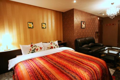 a bedroom with a bed and a black chair at Hotel Aura Resort Ⅰ Kashiba (Adult only) in Kashiba
