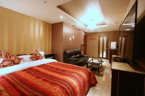 a hotel room with a bed and a chair at Hotel Aura Resort Ⅰ Kashiba (Adult only) in Kashiba