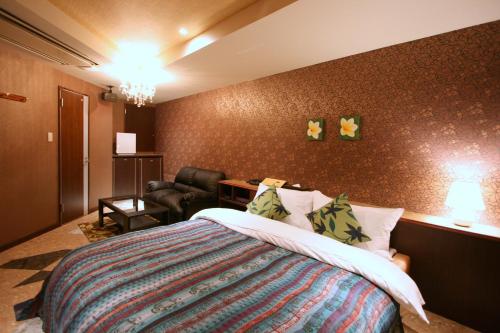 a hotel room with a bed and a chair at Hotel Aura Resort Ⅱ Kashiba (Adult Only) in Nara