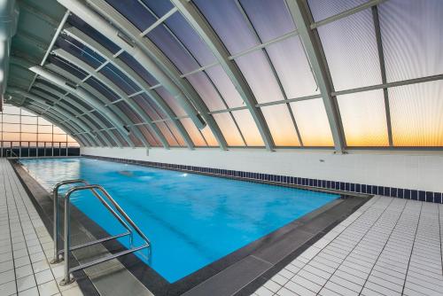 a large indoor swimming pool with a skylight at 3 Bedroom Darling Harbour Apartment in Sydney