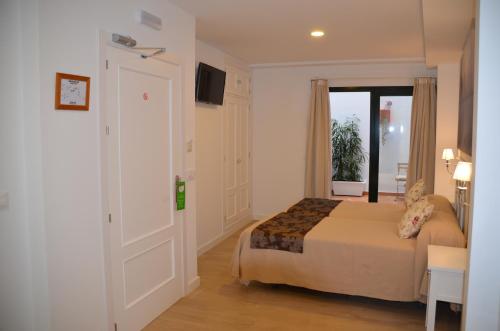 a bedroom with a bed and a sliding glass door at Hotel Doña Lina in Seville