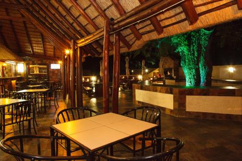 a restaurant with tables and chairs and a green tree at Swadini, A Forever Resort in Hoedspruit
