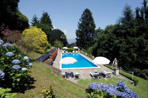 a swimming pool in a garden with umbrellas at Villa Claudia dei Marchesi Dal Pozzo in Belgirate