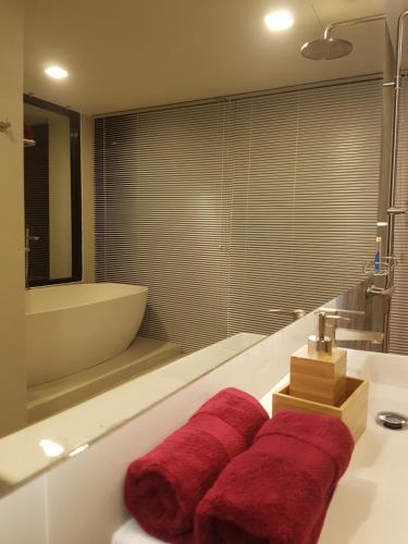 a bathroom with a tub and a sink with red towels at 8IK88 Resort - SHA Extra Plus in Por Bay