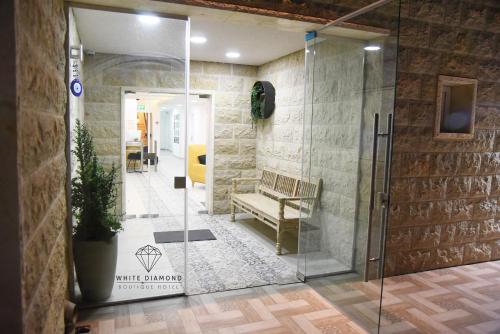 eine Glasdusche in einer Lobby mit einer Bank in der Unterkunft White Diamond in Madschdal Schams