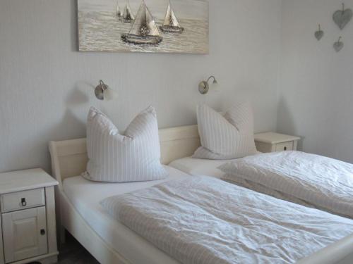 2 Betten mit weißer Bettwäsche und ein Gemälde an der Wand in der Unterkunft Ferienwohnung Kiefhuk in Elisabeth-Sophien-Koog