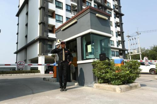 a man in a suit standing in front of a building at JK LIVING Hotel And Service Apartment in Chachoengsao