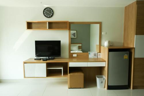 a room with a desk with a television and a clock at JK LIVING Hotel And Service Apartment in Chachoengsao