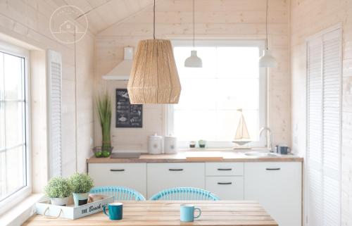 a kitchen with a table and a light fixture at Pastelowe Domki Wicie in Wicie