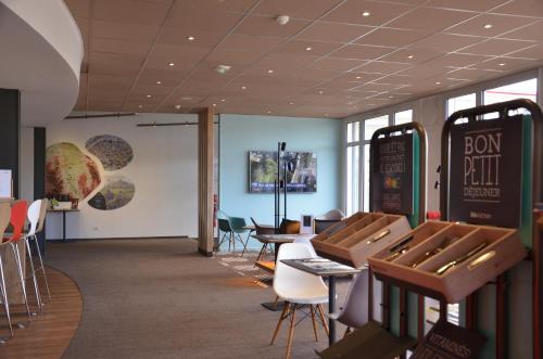 a dining room with tables and chairs and a sign on the wall at ibis Issoire in Issoire