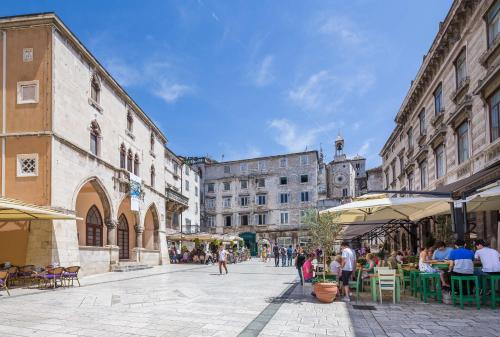a city street with people sitting at tables and a clock tower at VIP Rooms in Split