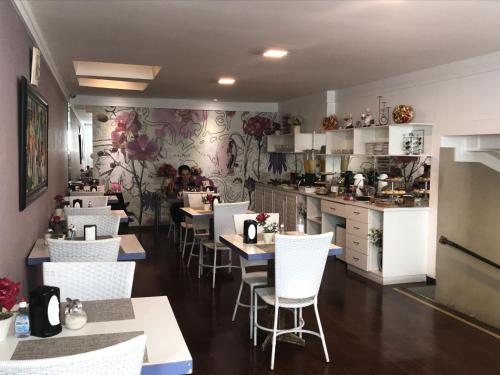 a restaurant with tables and white chairs and a kitchen at Aton Plaza Hotel in Goiânia
