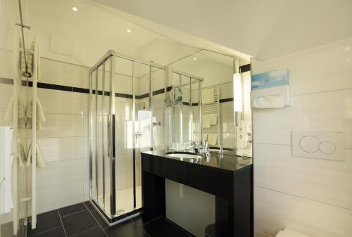 a bathroom with a sink and a glass shower at Hotel Waldesrand in Herford