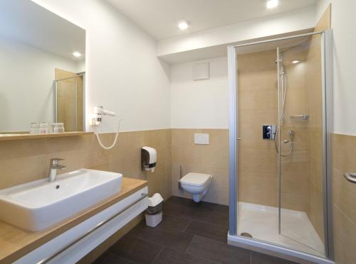 uma casa de banho com um lavatório, um chuveiro e um WC. em Landhotel Hopster em Rheine