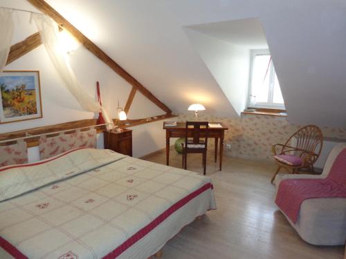 a bedroom with a bed and a table and a chair at B&B Les Cistelles in Saint-Nicolas-lès-Cîteaux