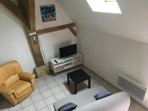 Una sala de estar con un sofá y un televisor. en La Huberdière, en Fondettes