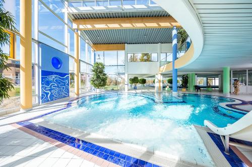 a large swimming pool in a building with a large window at Das Allgäu in Maierhöfen