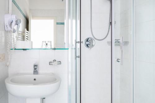 a white bathroom with a sink and a shower at Hotel St. James in Florence