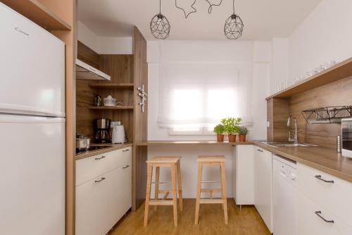 a kitchen with white cabinets and two bar stools at Miro in El Campello