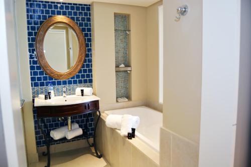 a bathroom with a sink and a tub and a mirror at Southern Sun Maputo in Maputo