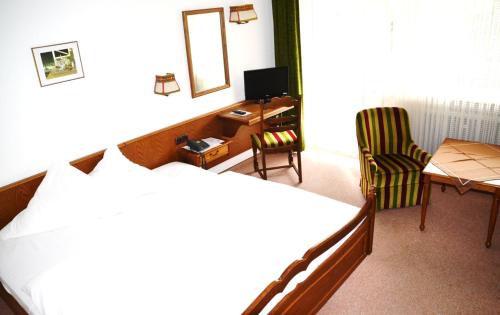 LindenfelsにあるHotel Wiesengrundのベッド2台、デスク、椅子が備わるホテルルームです。