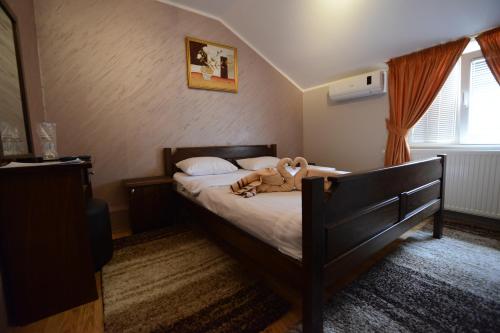 a bedroom with a bed with a stuffed animal on it at Garni Hotel Kaća in Kragujevac