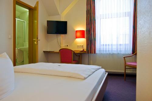 una camera d'albergo con letto e TV di Hotel Park Eckersbach a Zwickau