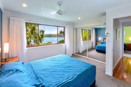- une chambre avec un lit bleu et une grande fenêtre dans l'établissement Heliconia 1 Hamilton Island 3 Bedroom Ocean Views with Golf Buggy, à Île Hamilton