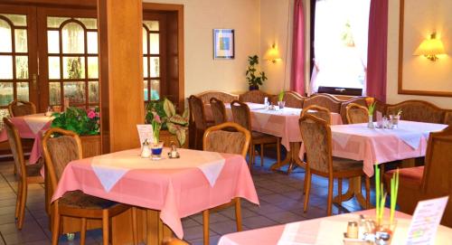 a dining room with tables and chairs with pink tablecloths at Hotel Wiesengrund in Lindenfels