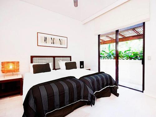 a white bedroom with a large bed and a window at Temple 121 Modern Spacious Palm Cove 2 Brm 2 Bth Resort Apartment With Courtyard in Palm Cove