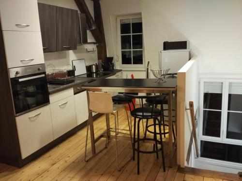 a kitchen with white cabinets and a black counter top at Loft Zola in Dijon