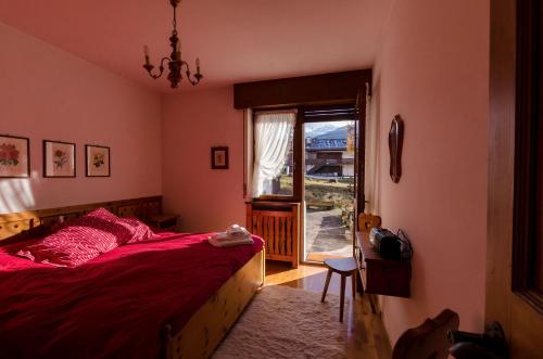 Schlafzimmer mit einem Bett mit einer roten Tagesdecke und einem Fenster in der Unterkunft Overlooking the Dolomites in Cortina d'Ampezzo