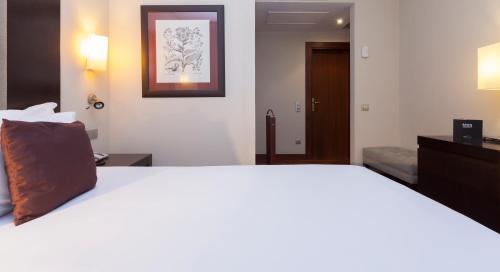 a bedroom with a large white bed with a picture on the wall at Hotel URH Palacio de Oriol in Santurce