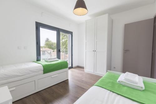 a white bedroom with two beds and a window at modern flat in Estoril