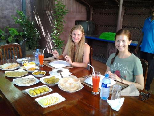 dos chicas sentadas en una mesa con comida en Pearl White House en Udawalawe