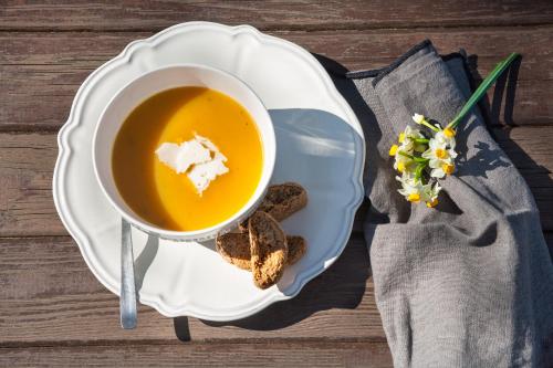 a cup of soup on a plate with bread and flowers at En Chora Vezitsa in Vitsa