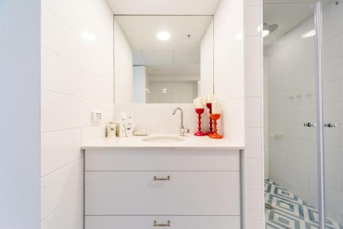 een witte badkamer met een wastafel en een spiegel bij Beach Apartment- breathtaking views with bomb shelter in Herzelia 