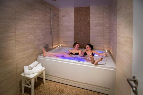 Deux femmes sont assises dans une baignoire dans l'établissement Wellness Hotel GREEN PARADISE, à Pirkenhammer