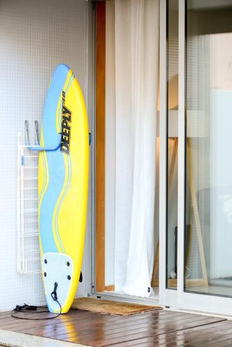 a yellow and blue surfboard is leaning against a door at By the Sea Apartment with Large Private Terrace in Matosinhos
