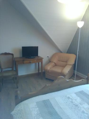 ein Schlafzimmer mit einem Bett, einem Stuhl und einem TV in der Unterkunft Chez Nicole in Marconne
