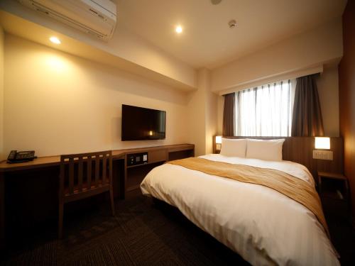 Dormy Inn Hon-Hachinohe في هاتشينوه: غرفة فندقية بسرير وتلفزيون بشاشة مسطحة