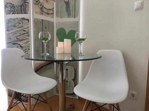 ポンタ・デルガダにあるAzores Paim Apartmentの白い椅子2脚、ガラステーブル(ワイングラス付)