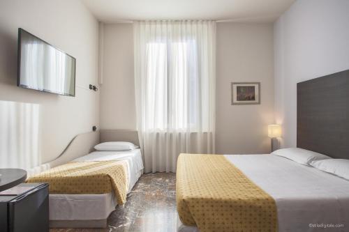 a hotel room with two beds and a television at Boutique Hotel Liberty 1904 in Bologna