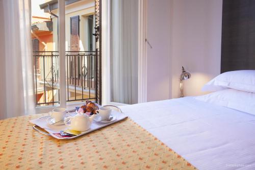 Una cama con una bandeja con dos tazas y un plato de comida. en Boutique Hotel Liberty 1904, en Bolonia