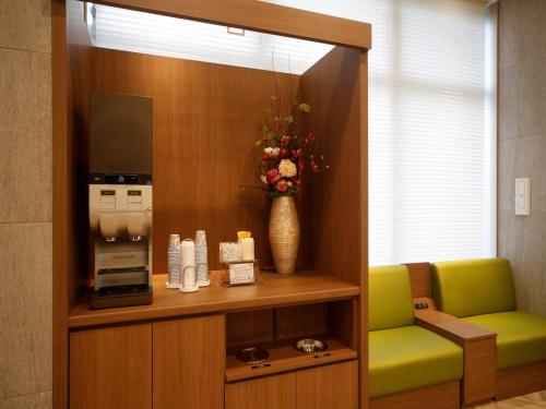 a room with a coffee machine and a green chair at Dormy Inn Hon-Hachinohe in Hachinohe